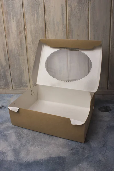 Caixa de papelão com uma tampa transparente em um fundo claro — Fotografia de Stock