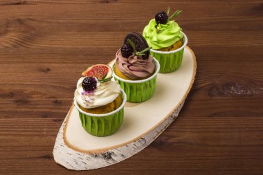 Bir ahşap tahta üzerinde üç top kek. Ahşap arka plan.