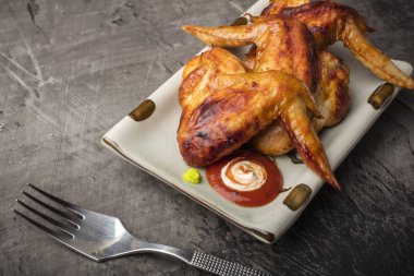 Tavuk kanadı karanlık bir arka plan üzerine bir tabak. Çıtır kızarmış tavuk 