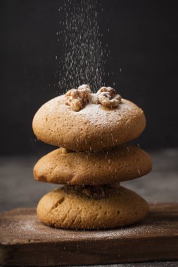 Ceviz ahşap bir gemide tatlım kurabiye ile pudra şekeri serpilir. Koyu arka plan. ev yapımı yiyecek 1