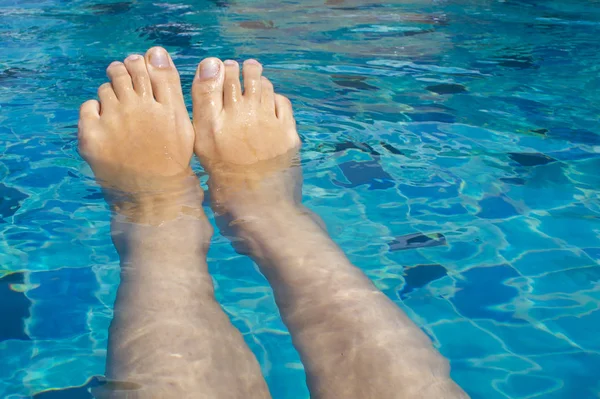 Beautiful female legs relax in clear water. Rest in the pool
