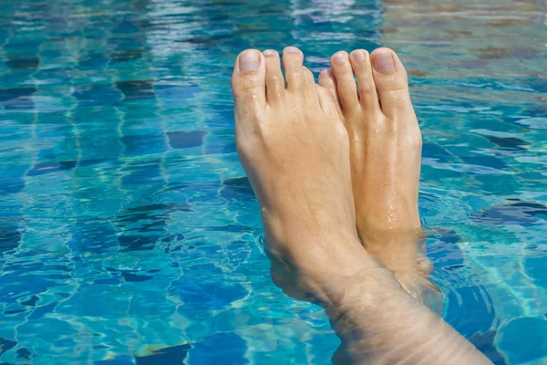 Beautiful female legs relax in clear water. Rest in the pool