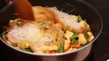 Pişirme el karıştırma, kızarmış tavuk, sebzeli hindi ve cam erişte. Tavada yemek pişirmek