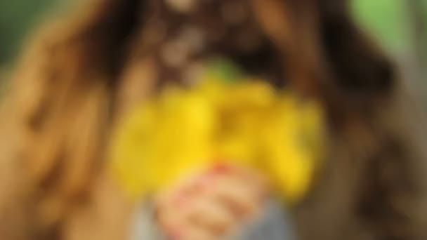 Girl holding a bouquet of yellow leaves in her hands and plays with it — Stock Video