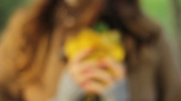 fille tenant un bouquet de feuilles jaunes dans ses mains et joue avec elle 