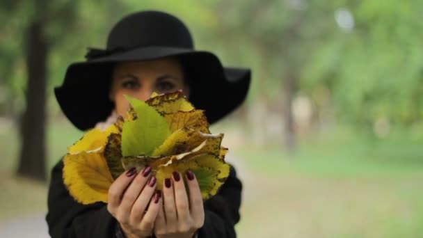 Mélange de deux coups de la fille aux cheveux noirs qui joue avec les feuilles — Video