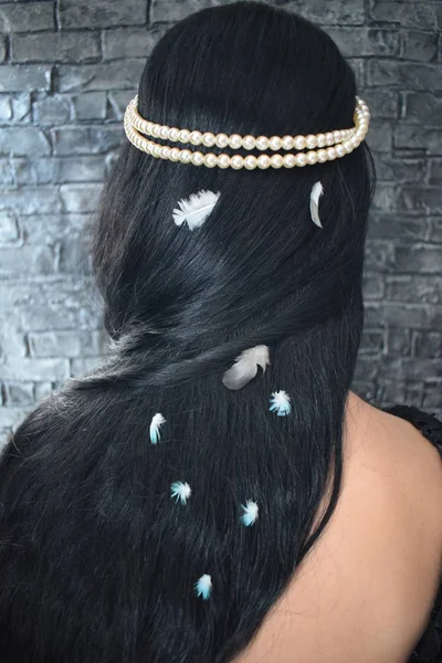 Girl whit beautiful black hair, decorated with pearls and feathers — Stock Photo, Image