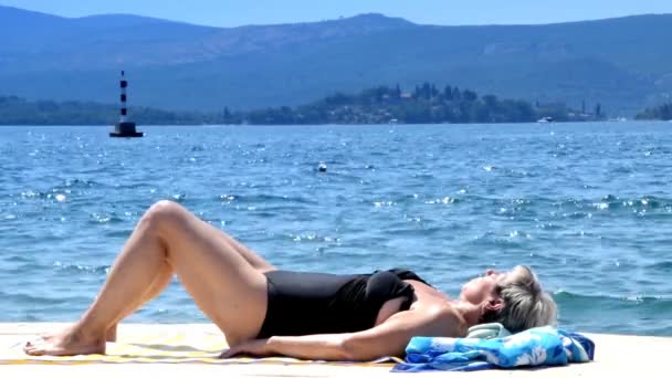 Mulher deitada na doca junto ao mar — Vídeo de Stock