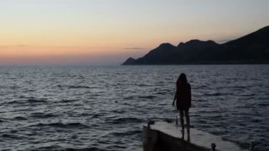 iskelede dışarı ve Denizi izlemek giden bir kız silüeti