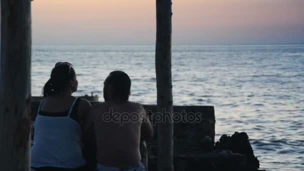 Vriend en vriendin genieten van de zonsondergang aan zee — Stockvideo