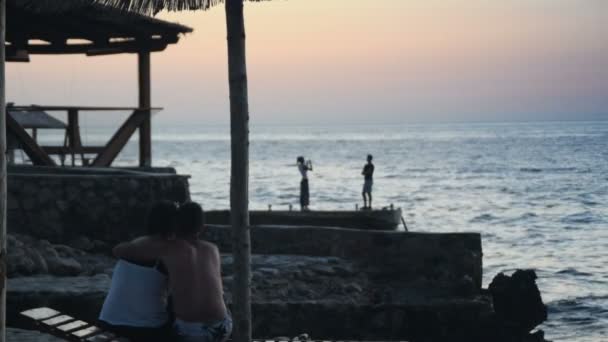 Αγάπη ζευγάρι μιλώντας και παρακολουθώντας το ηλιοβασίλεμα από την παραλία — Αρχείο Βίντεο
