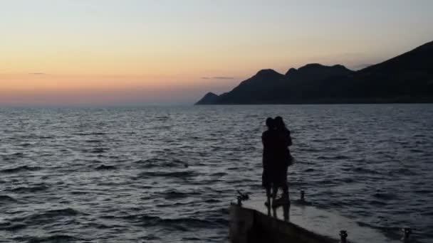 Silhouet van een paar die omarmen op het strand bij zonsondergang — Stockvideo