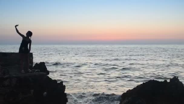 Silhouet van een jong meisje op het strand, die fotograferen selfie — Stockvideo