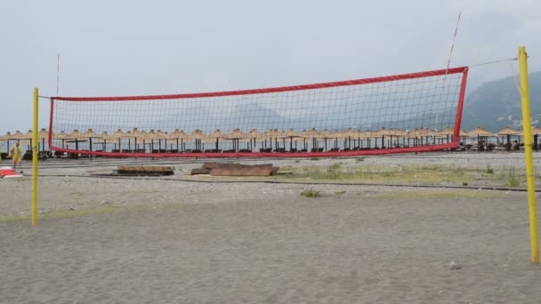 Volleyball court on the beach, people passing by — Stock Video