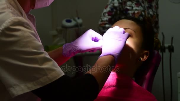 Colocando afastador de bochechas e sucção dentária na boca da menina — Vídeo de Stock