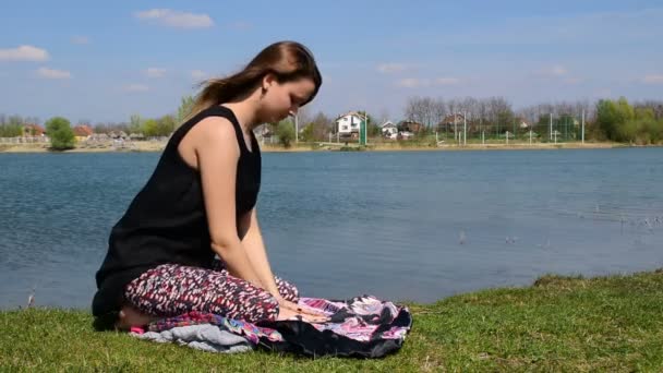 Young woman doing yoga beside calm waters — Stock Video