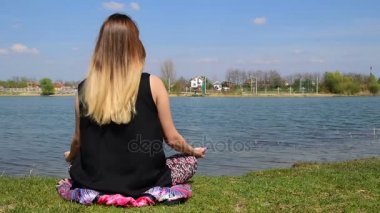 Genç kız suya yakın lotus pozisyonda meditasyon