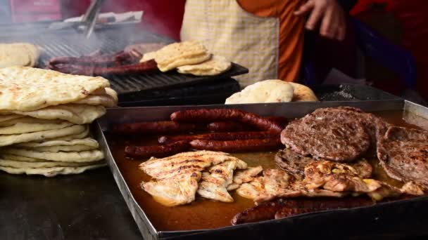 Hamburger, carne, pane, salsicce sono fritti su una griglia, le mani degli uomini li girano — Video Stock