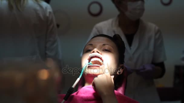 Dziewczyna pacjent z otwartymi ustami, drapanie palcem całej twarzy, a ona czeka na stomatologa — Wideo stockowe