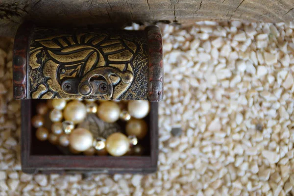 Un viejo joyero ornamental y un collar de perlas blancas, una maleta con un tesoro, desde arriba en el lado izquierdo —  Fotos de Stock