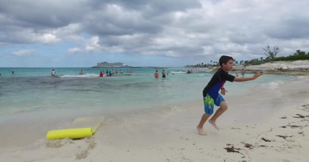 El chico está jugando en la playa, cerca del agua — Vídeos de Stock