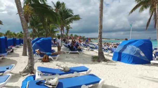 Tourists enjoyning on deckchairs and under the awning on the beach — Stock Video