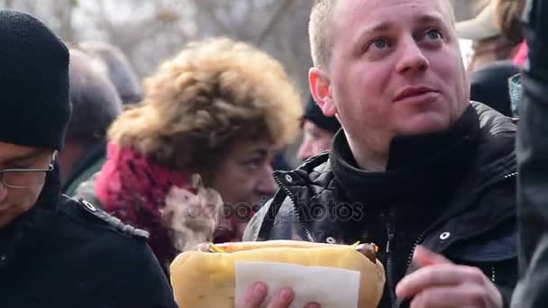 Die Leute essen heiße Sandwiches mit Wurst, während Rauch aus ihr quillt — Stockvideo