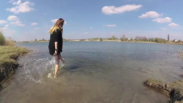 Mujer joven se divierte, y salpicar la superficie del agua con el pie, cámara lenta y marcha atrás — Vídeo de stock
