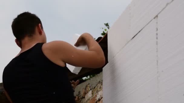 Hombre reparando la pared, cortando espuma de poliestireno y pegando — Vídeo de stock