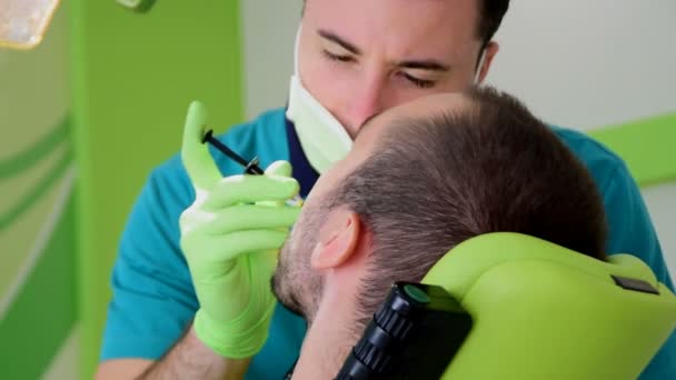 Um jovem dentista masculino dá anestesia a um paciente do sexo masculino — Vídeo de Stock