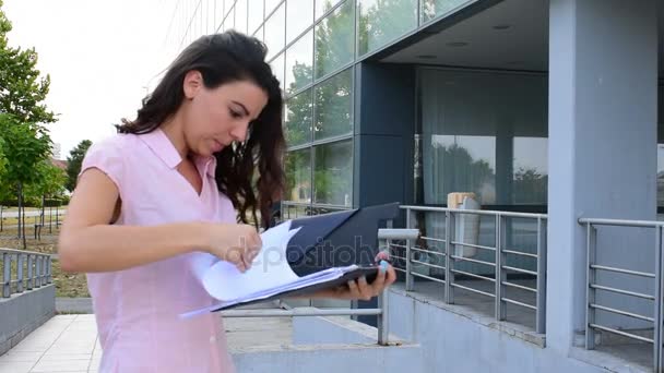 La ragazza guarda un mucchio di carta mentre l'uomo con la tavoletta si avvicina a lei — Video Stock