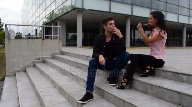 genç adam ve genç kadın merdivenleri ve duman sigara üzerinde oturuyordu