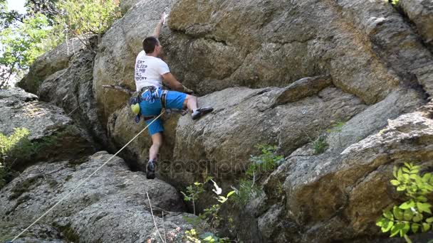 Mladší muž leze na skálu s rock, horolezecké vybavení — Stock video
