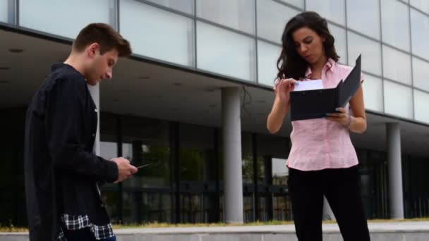 Twee vrienden praten terwijl ze de documenten controleert, en hij naar iets op de tablet zoekt — Stockvideo