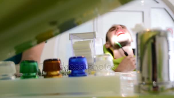 Ändra fokus, Dentalutrustning på kontoret, i fokus, ung stilig man som sitter på stolen medan hans unga manliga tandläkare åtgärdar sin teeths — Stockvideo