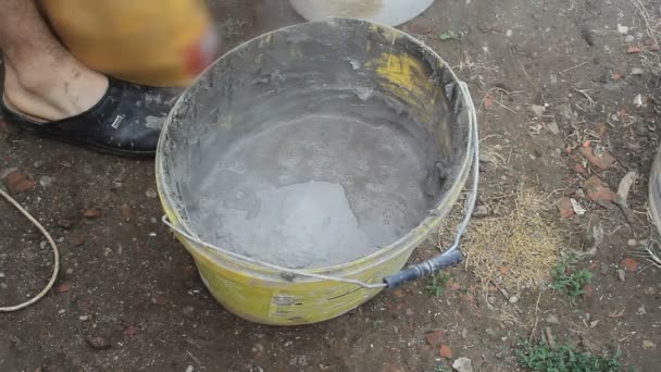 Homem mistura cola com broca de concreto. Homem mistura de cola de concreto com broca longa especial anexada à máquina de perfuração, misturador de mão giratória misturando argamassa de cimento para paredes de gesso — Vídeo de Stock