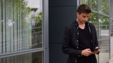 genç bir adam tarafından bir cam bina geçen süre telefonunu yazarak blacka içinde