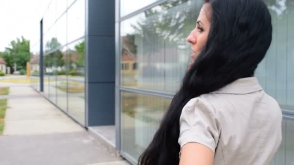 An attractive black-haired woman is talking on the phone — Stock Video