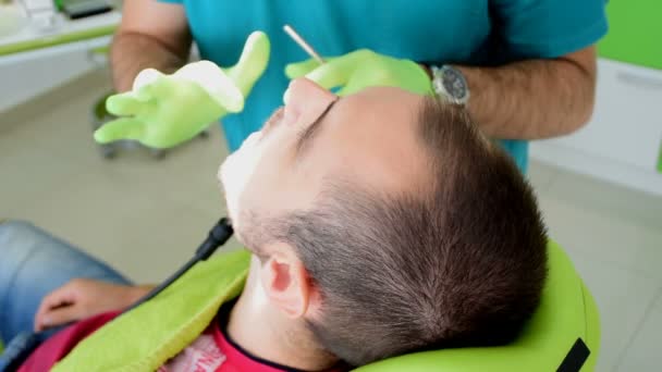 Un joven quita la caries de los dientes al dentista — Vídeo de stock