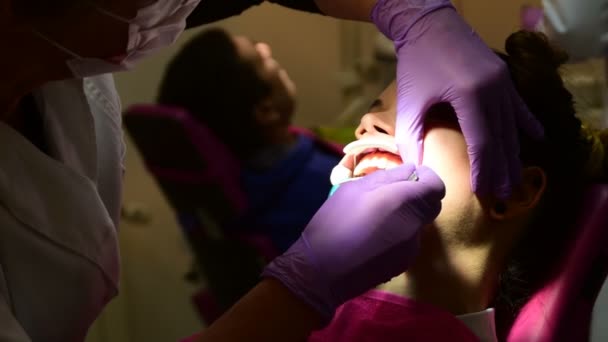 Dentista está colocando aparelho nos dentes de uma jovem — Vídeo de Stock