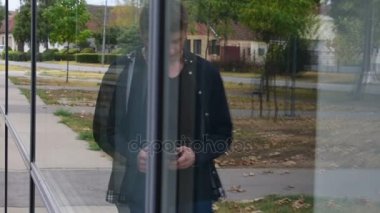 Bina, genç bir adam için cam bir yansıması dan bir cam dururken telefonuna yazarak blacka çekici genç adam