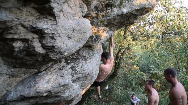 Mladší muž šplhá ke skále bez horolezecké vybavení, Free solo, tři mladí muži bez košile — Stock video