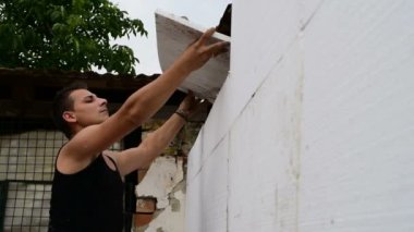 Köpük yalıtım, onarım yapan genç bir erkek elinde duvara çalışmak.