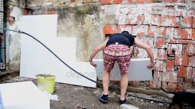 Köpük yalıtım, onarım yapan genç erkek arka duvardaki çalışır