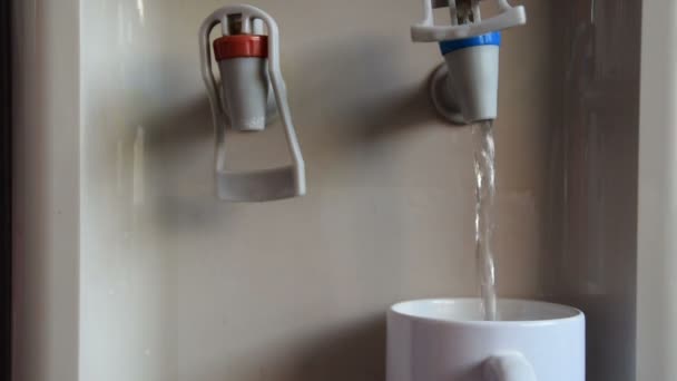 La mano de una mujer pone una taza blanca para llenar con agua de la máquina de agua — Vídeos de Stock