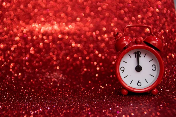 the red clock to the right of the photo ticks at noon, midnight, on a red background with a glitter  where you can write your message