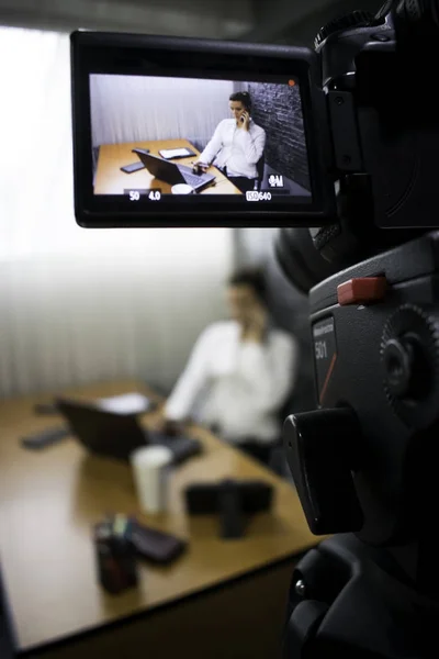 Video kamera bir genç iş kadını bir dizüstü bilgisayar önünde bir masada oturan ve bir telefon görüşmesi vuruyor