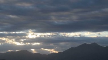 Bulutlu gökyüzü ve güneş dağların üstünde