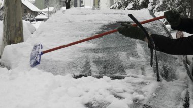 Adamın elleri arabanın ön camındaki karı temizliyor..