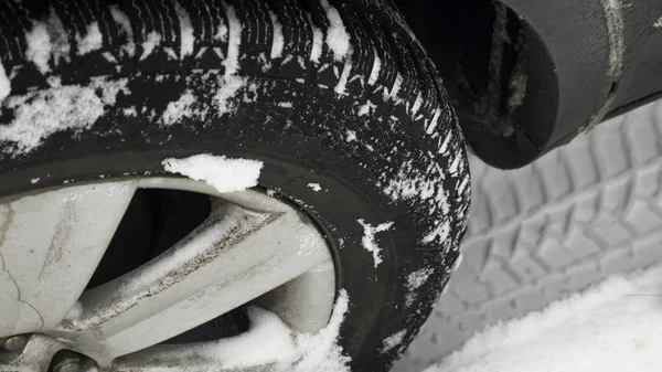 Close up of a cars tires on a snowy road. Transportation and safety concept. Snowy winter road with tire tracks in snow and tire. Car tires on winter road covered with snow.
